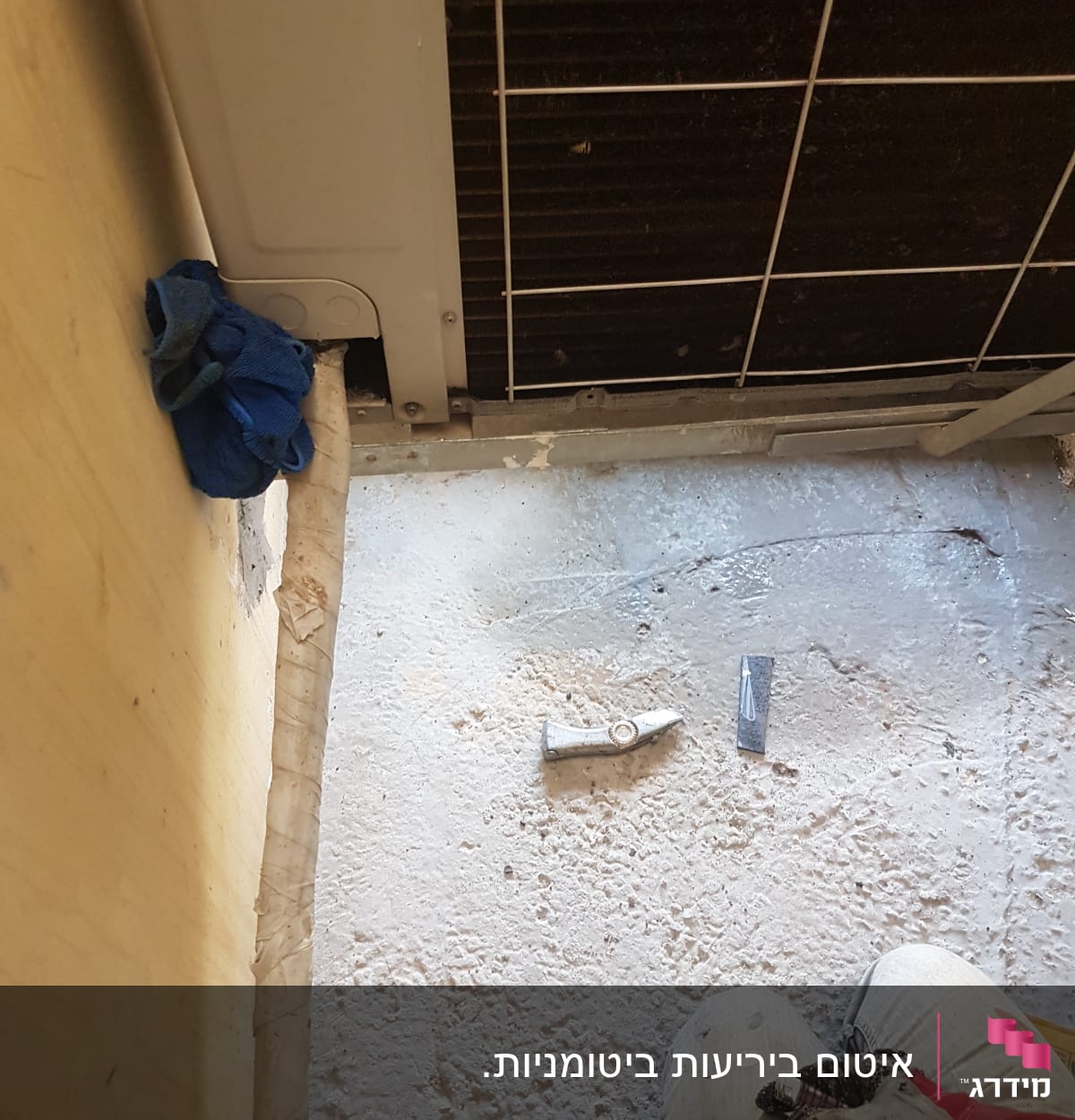 אדם עובד על איטום ליד מזגן עם כלים